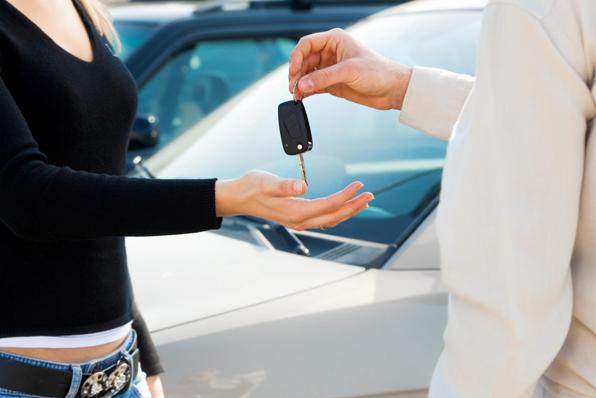 cropped view of man in car dealership giving car keys to client